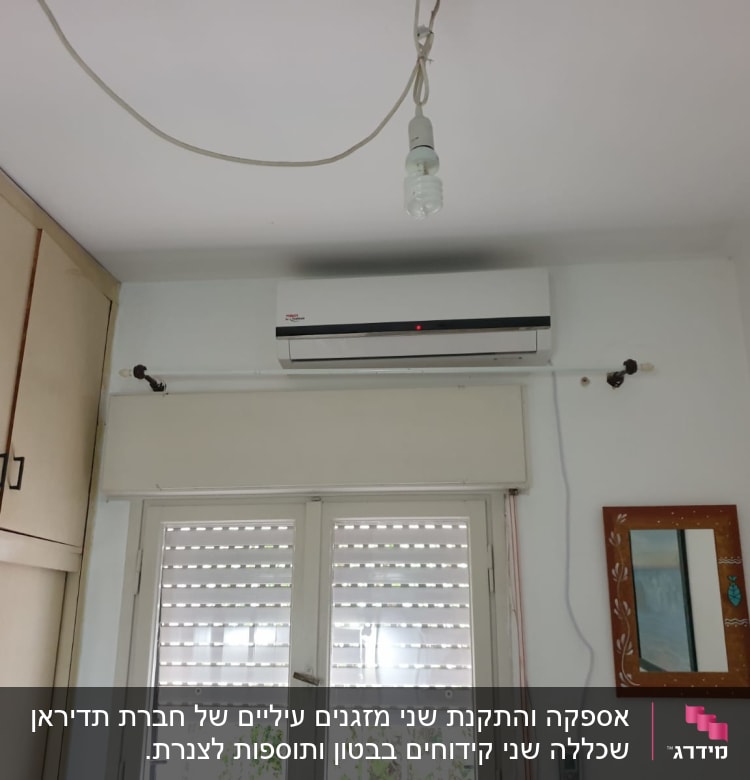 מזגן מותקן על קיר מעל חלון עם תריסים